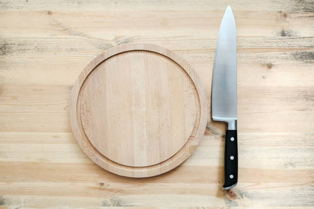 istock Large sharp knife and a round, wooden cutting board on a table in the kitchen. Copy space. Top view. 1352071231