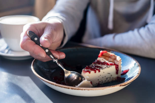 istock Delicious cheesecake breaks off with a spoon from a large piece on a beautiful plate, on a blurred background a cup of cappuccino. 1352071282