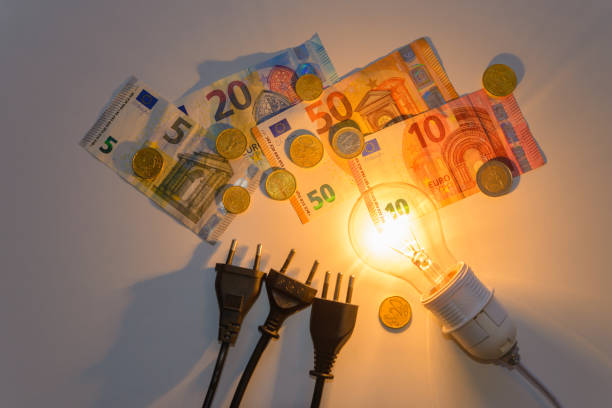 Light bulb on, with electrical plugs, banknotes and coins. Energy tariffs. stock photo
