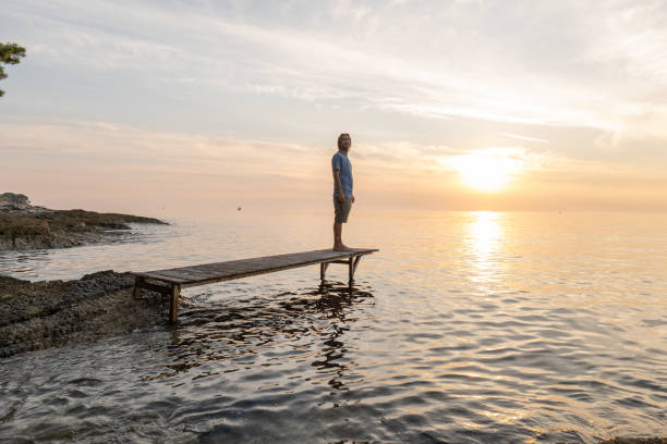 istock Young man relaxing on pier at sunset 1352071389