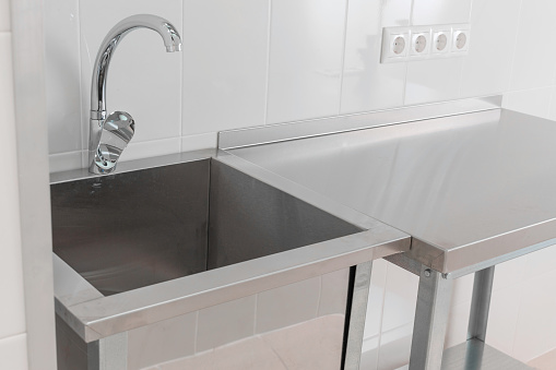 Design of the working area of the cafe kitchen, chrome sink and faucet, a place for washing dishes in a restaurant.