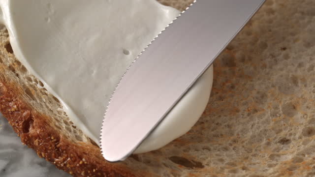 Spreading cream cheese on bread