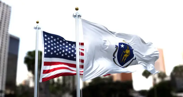 Photo of the flag of the US state of Massachusetts waving in the wind with the American flag blurred in the background