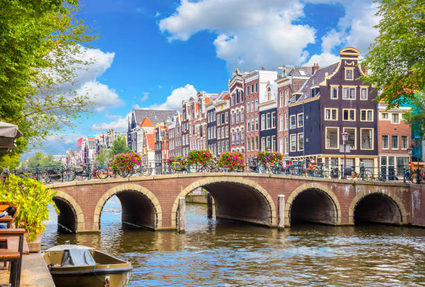 amsterdam downtown - amstel river, old houses and a bridge. nice view of the famous city of amsterdam. travel to europe. - nederlandse vlag fotos stockfoto's en -beelden