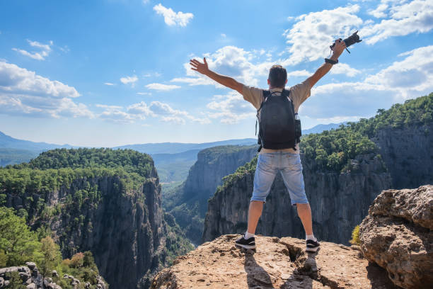 istock Faceless man with photo camera on cliff 1352076131