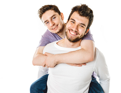 A Young gay couple standing together over isolated background