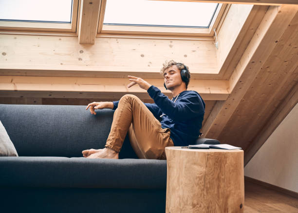 young man relaxes in brightly lit, modern apartment - brightly lit audio imagens e fotografias de stock