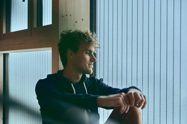 istock View of young man relaxing by window, in thought 1352078323