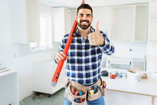 istock Concentrated young man work with white cabinet in the kitchen with level 1352080053