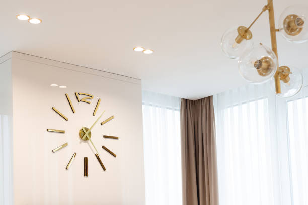 istock A huge clock in gold color on the wall in a modern beige interior. Interior Design. Soft selective focus, artistic noise. 1352080816