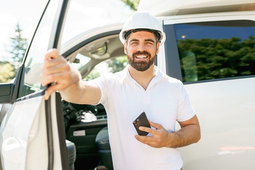 A Man engineer builder wearing a white hard hat, shirt in front of his pickup using cellphone
