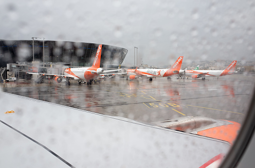 Nice, France - 30 October, 2021:  Three easyJet passenger jets attached to Nice airport terminal on a rainy day, shot from another easyJet plane taxiing on the apron.