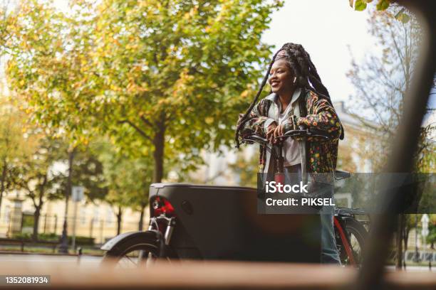 Woman Using Cargo Bike In Urban Area Stock Photo - Download Image Now - Cargo Bike, Black People, One Person