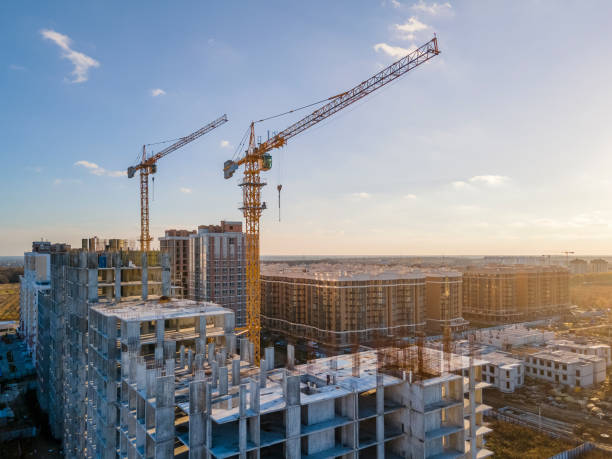 Cranes on the construction site surrounded by new real estates. Cranes on the construction site surrounded by new real estates. Scenic aerial photo of growing city districts construction industry stock pictures, royalty-free photos & images