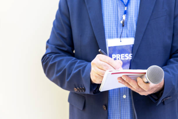 periodista con pase de prensa en conferencia de prensa o evento de medios, sosteniendo micrófono, escribiendo notas - credencial de prensa fotografías e imágenes de stock