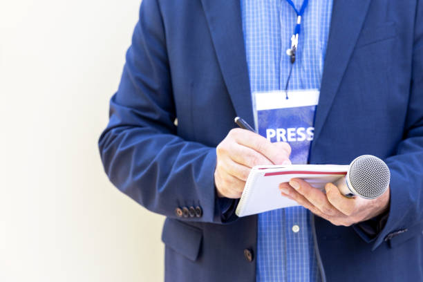 journalist with press pass at news conference or media event, holding microphone, writing notes - newspaper the media paper blank imagens e fotografias de stock