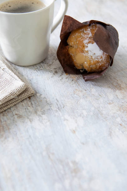 Mug of coffee and a lemon muffin on a rustic table with copy space