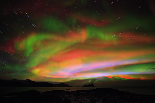 Northern landscape. Winter background with green Aurora Borealis and stars trails