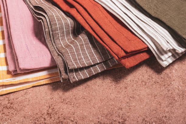 Stack of colored serving napkins on beige background
