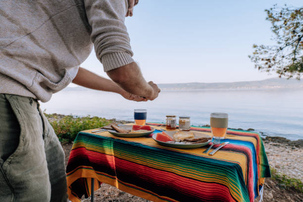 Man prepares breakfast picnic table by the sea