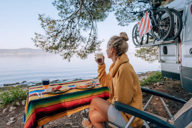 Woman enjoys breakfast near her van, beach view