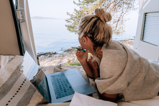 View of woman working on her laptop from a wild camping spot, Croatia.
Digital nomad lifestyle