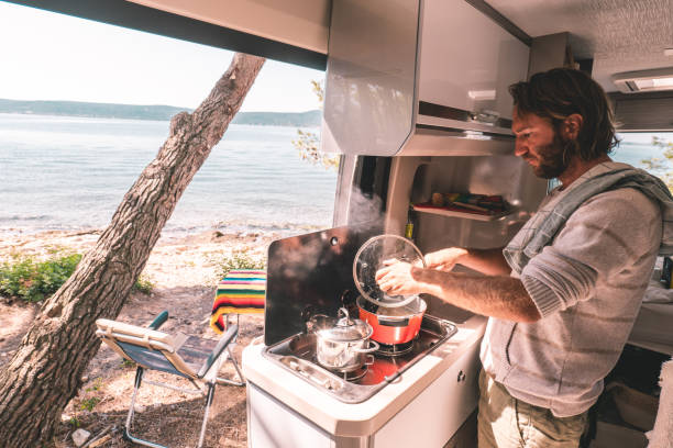 istock Man cooking in a camper-van, ocean view 1352085872