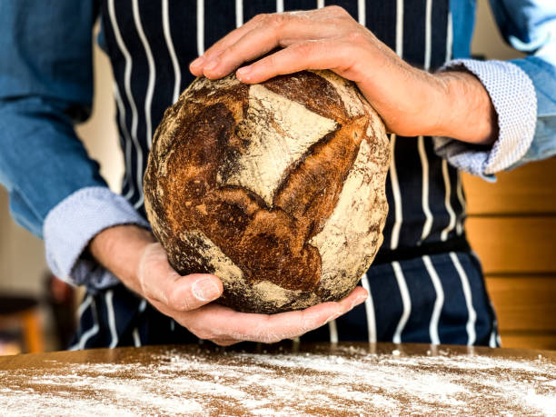 istock Male hands are holding freshly baked sourdough bread 1352087655