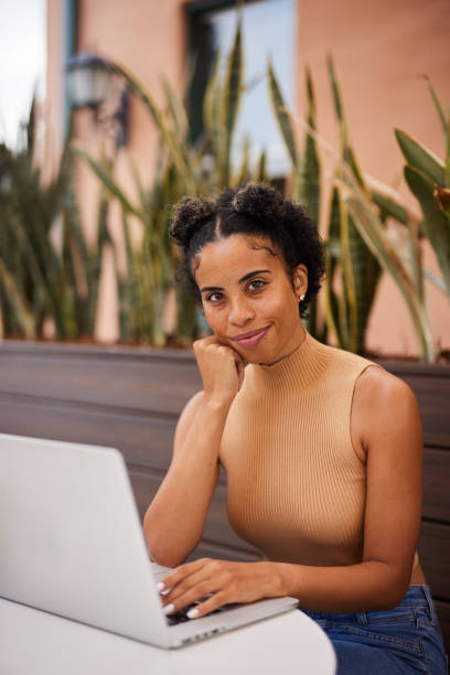 istock Smiling young woman working on a laptop outside at a cafe table 1352087833