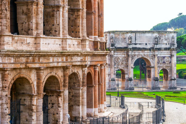 a glimpse of the imposing coliseum and the arch of constantine in the heart of the imperial forums in rome - stone textured italian culture textured effect imagens e fotografias de stock