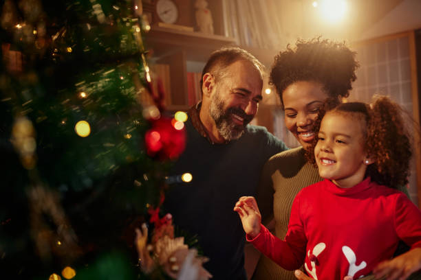 Parents helping her daughter to decorate the Christmas tree stock photo