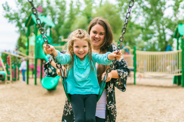 Happy little girl is playground having fun on swing stock photo