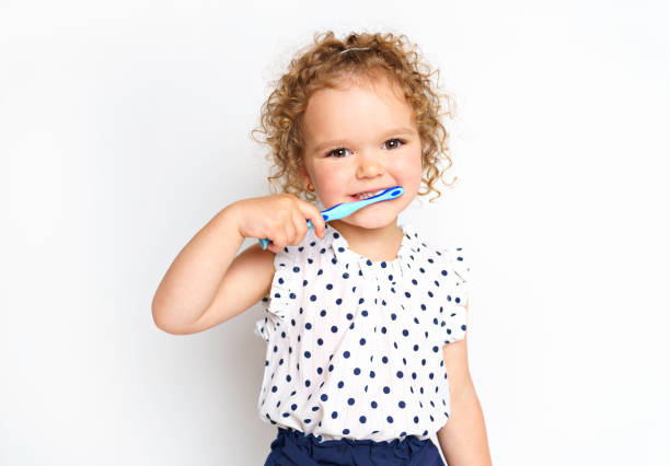 little smiling curly girl brushing teeth portrait - hairstyle crest imagens e fotografias de stock