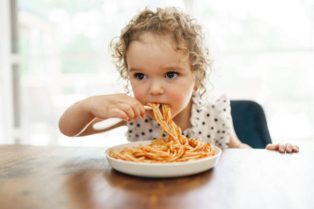 istock hungry little girl eating spaghetti at home kitchen 1352091407