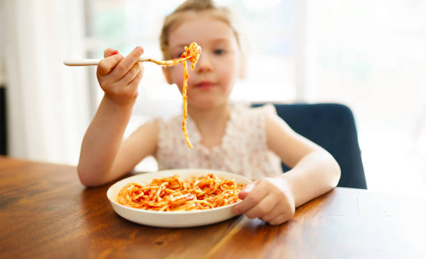 istock hungry little girl eating spaghetti at home kitchen 1352091408