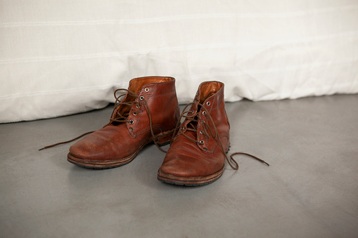 Front shot of brown leather shoes on floor next to bed