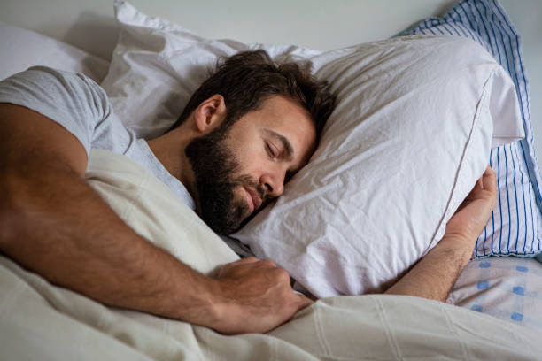 istock Young adult man lying in bed while sleeping 1352093423