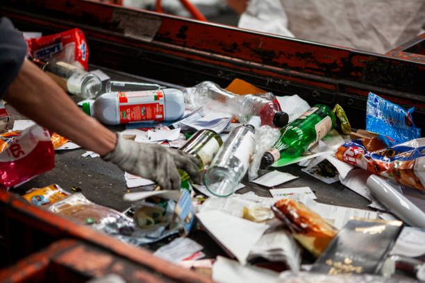 Worker selecting recycable materials on conveyor belt Close-up of worker selecting recycable materials on conveyor belt at a waste sorting center recycling center stock pictures, royalty-free photos & images