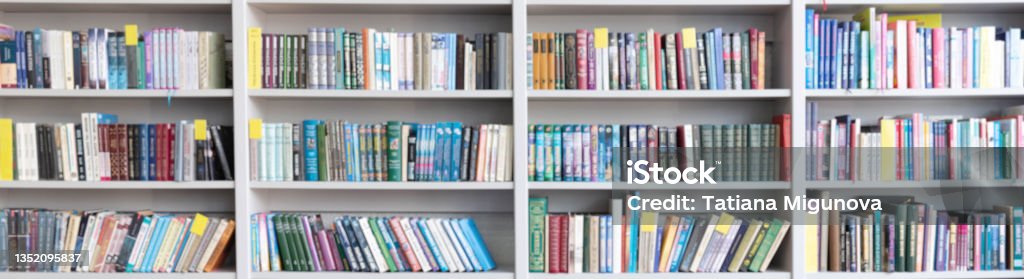 Library with bookcases. Many different books on the shelves. Large selection of books in a bookcase. Blur background Blurred image of a library with bookcases. Many different books on the shelves. Large selection of books in a bookcase. Blurred background. Book Stock Photo