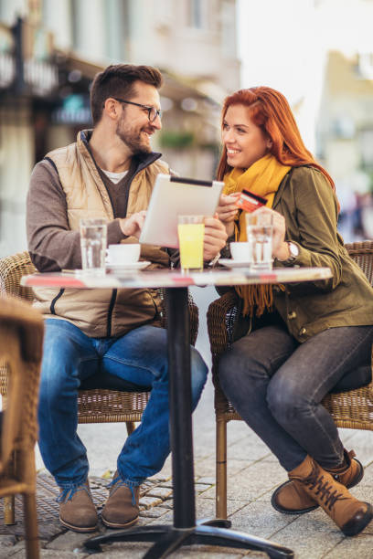 istock Young couple in a cafe using digital tablet and credit card. 1352095855