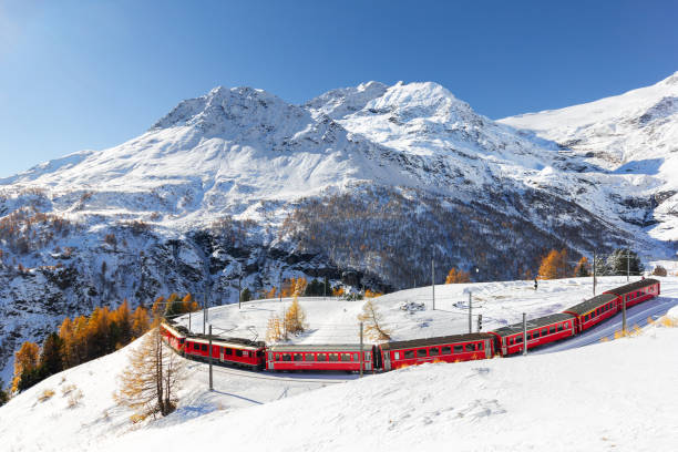 赤い列車は高いアルプ・グラムでタイトな180°カーブで列車の線路を通過しています - rhätische bahn ストックフォトと画像
