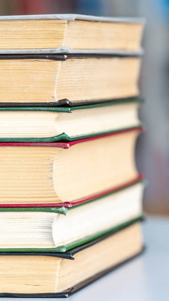 istock Books stack on wooden table and blurred bookshelf in library hall 1352095936