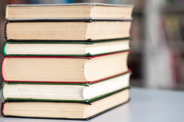 istock Books stack on wooden table and blurred bookshelf in library hall 1352095964