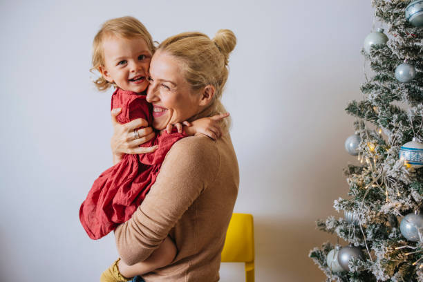 wesoła matka obejmująca córkę w domu - standing family golf loving zdjęcia i obrazy z banku zdjęć