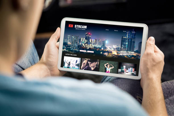 Movie and series stream VOD service in tablet. Watching on demand tv show or film online. Man choosing video entertainment from subscription media catalogue. stock photo