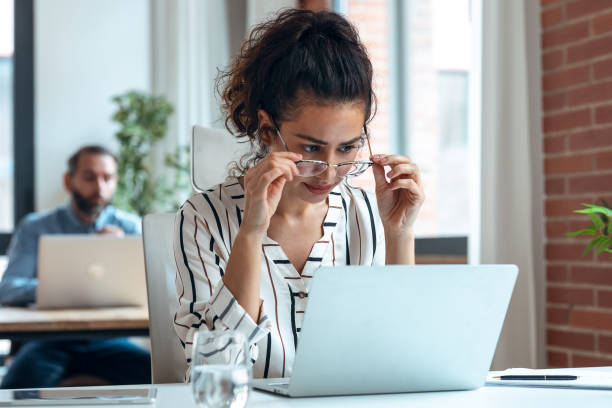 istock Tired business woman with headache looking uncomfortable while working with computer in the office 1352099756
