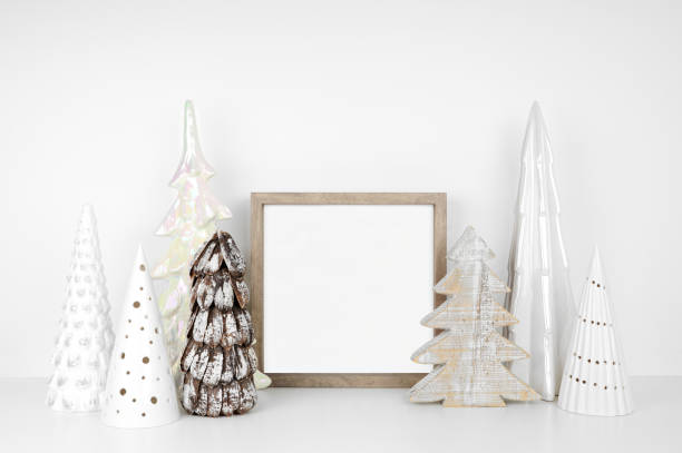istock Christmas mock up with wood frame and white tree decor on a white shelf against a white wall 1352099939