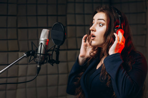 istock Female with microphone recording a voice for dubbing in music studio 1352100479