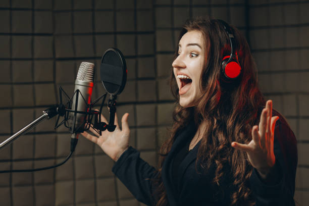 istock Female with microphone recording a voice for dubbing in music studio 1352100480
