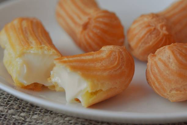 istock mini cakes eclairs on a plate. Broken eclair with dripping cream filling 1352102042